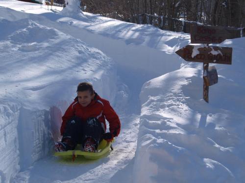 a young boy riding a snowboard down a snow bank at Il Borgo Dei Celti in Fiumalbo