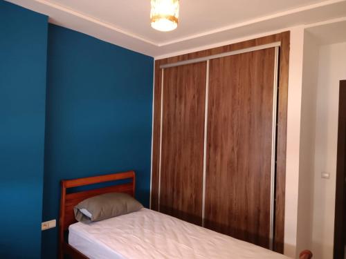 a blue bedroom with a bed and a wooden cabinet at place to be saidia in Saïdia