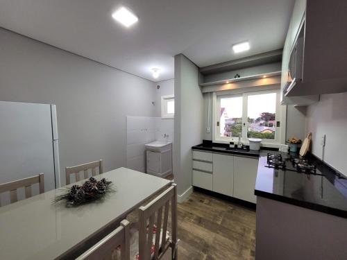 cocina con armarios blancos y encimera en Apartamento Residencial Villa di Vienna en Nova Petrópolis