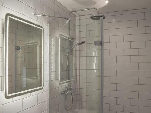 a shower with a glass door and a mirror at Willows View in Etchingham