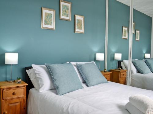 a bedroom with blue walls and a bed with blue pillows at New Trend in Chapel Saint Leonards