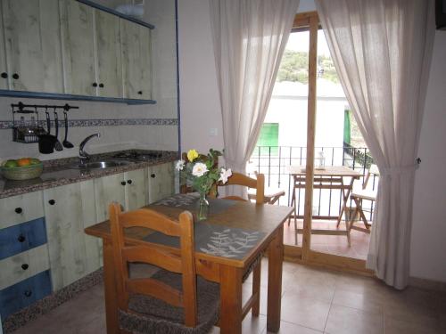 a kitchen with a table with a vase of flowers on it at Casa María Jesús in Pórtugos