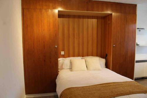 Bett mit einem Kopfteil aus Holz in einem Zimmer in der Unterkunft Modern studio apartment with parking in Chatham