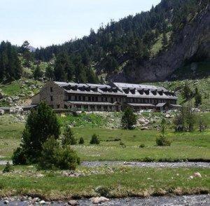 a building in a field next to a mountain at Hotel Hospital de Benasque in Benasque