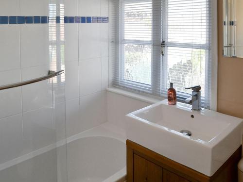 a white bathroom with a sink and a shower at Courtyard Cottage in Framlingham