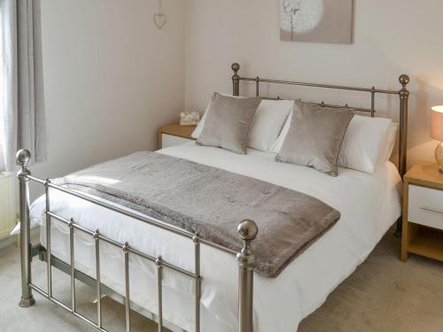 sypialnia z metalowym łóżkiem z białą pościelą i poduszkami w obiekcie Courtyard Cottage w mieście Framlingham