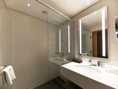 a bathroom with a sink and a mirror at Mercure Ambassador Ulsan in Ulsan