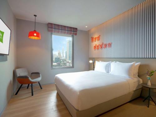 een slaapkamer met een groot wit bed en een raam bij ibis Styles Bangkok Sukhumvit 4 in Bangkok