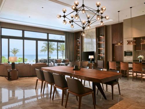 a dining room and living room with a table and chairs at Mövenpick Villas & Residences Phu Quoc in Phu Quoc
