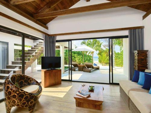 a living room with a couch and a tv at Mӧvenpick Resort Kuredhivaru Maldives in Manadhoo