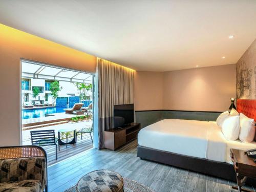 Mercure Langkawi Pantai Cenang في بانتايْ سينانج: غرفه فندقيه بسرير وشرفه