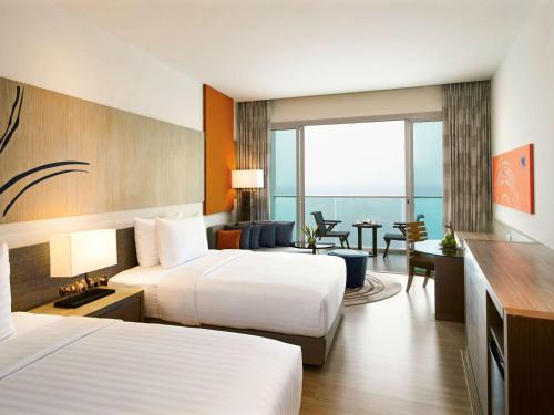 a hotel room with two beds and a view of the ocean at Mövenpick Siam Hotel Na Jomtien Pattaya in Na Jomtien