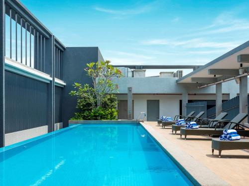 a swimming pool with lounge chairs next to a building at Mercure Kuala Lumpur Glenmarie in Shah Alam