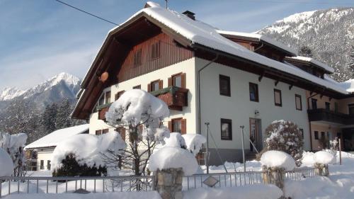 a house covered in snow with mountains in the background at Gästehaus im Wiesengrund in Sankt Stefan an der Gail