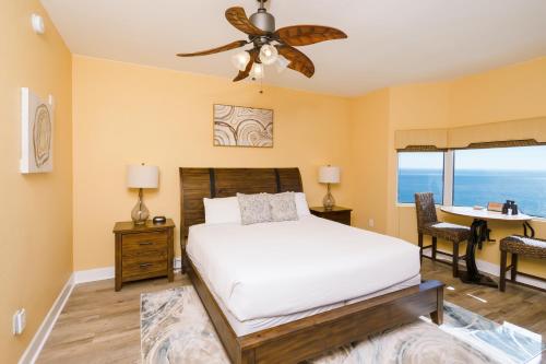 Schlafzimmer mit einem Bett, einem Deckenventilator und einem Schreibtisch in der Unterkunft Tidewater2808 in Panama City Beach