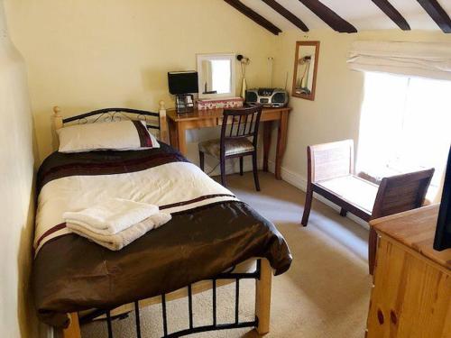 a bedroom with a bed and a desk with a chair at Ashley Cottage in Colsterworth