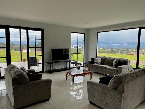 sala de estar con 2 sofás y TV de pantalla plana en Altos de Tababela en Tababela