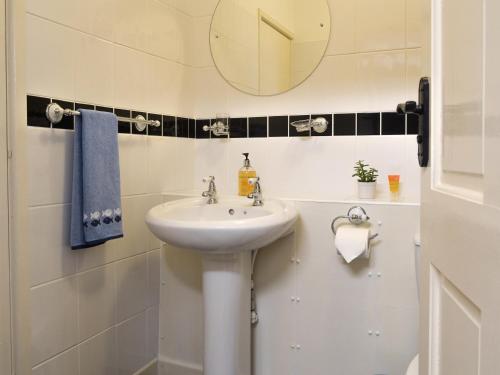 a white bathroom with a sink and a mirror at The Snug in Amlwch