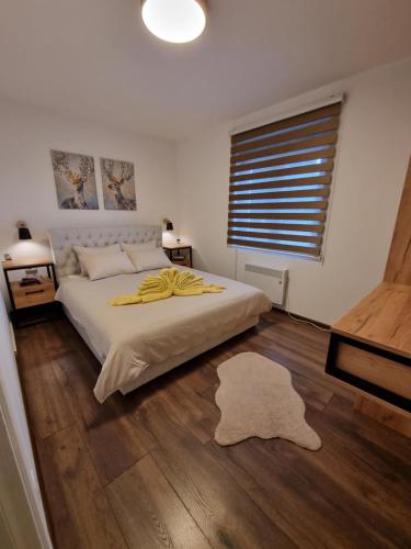 a bedroom with a bed with a yellow blanket on it at Zlatar Holidays Apartmani in Nova Varoš