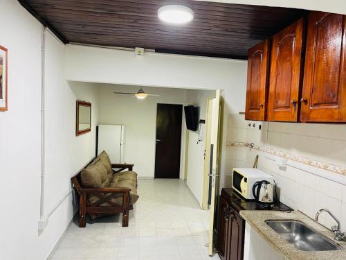 una cocina con fregadero y un sofá en una habitación en Departamento temporario jr en Corrientes