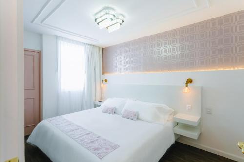a hotel room with a white bed and a window at Casa Oxa Hotel in Querétaro