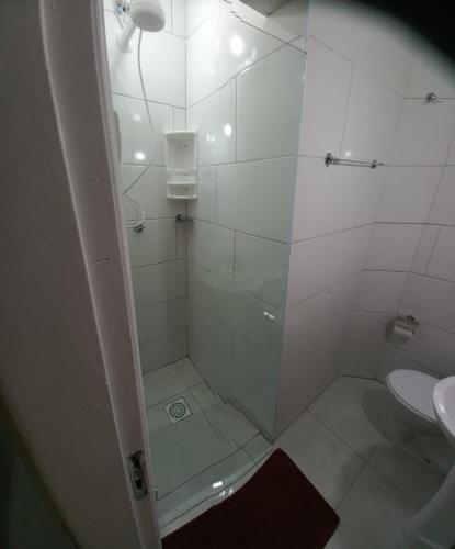 a white bathroom with a shower and a sink at Pousada Sol da Manhã in Guarujá