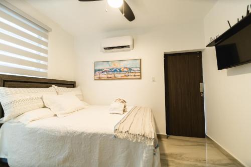 a bedroom with a white bed and a tv at Casa Sofía, Aventura Romántica en Rincón in Rincon
