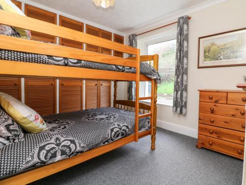 a bedroom with two bunk beds and a dresser at Hele Beach in Ilfracombe