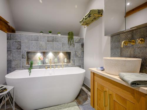 ein Badezimmer mit einer großen weißen Badewanne und einem Waschbecken in der Unterkunft Dassett View in Fenny Compton