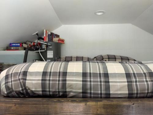 a bed with a plaid pillow on the floor at Catskills tiny house cabin in Livingston Manor