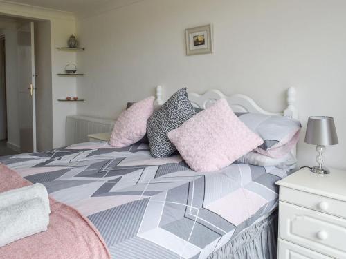 a bedroom with a bed with pink and grey pillows at Meadow View in Tregoney