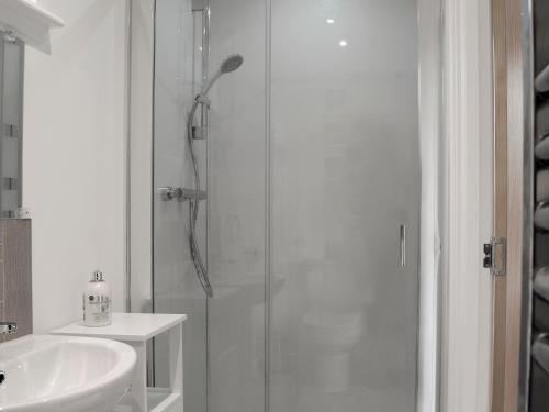 baño blanco con ducha y lavamanos en Barn Owl Cottage, en Inver