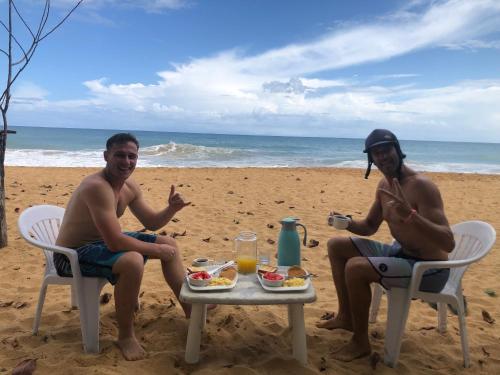 a man and woman sitting at a table on the beach at Playa Bluff Lodge in Bocas del Toro
