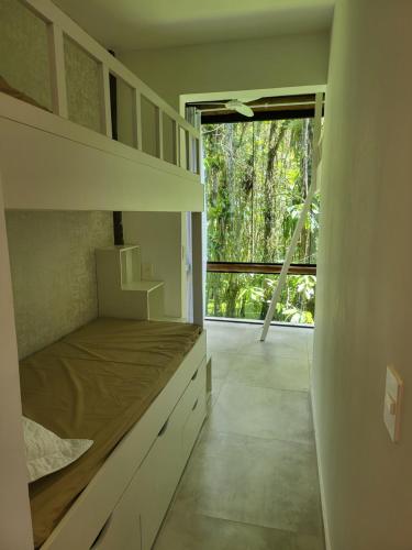 - une chambre avec un lit et une grande fenêtre dans l'établissement Maresias Beach Housing - Mata Azul, à São Sebastião