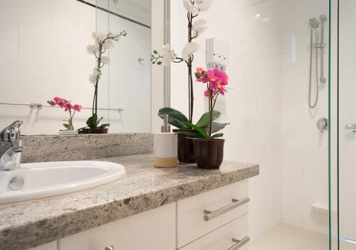 a bathroom with a sink and flowers on a counter at The Portsea Hideaway in Portsea