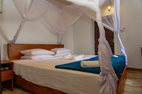 a bedroom with a canopy bed with white sheets and pillows at Aurelia Zanzibar in Ngambo