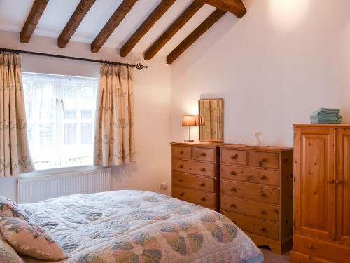 a bedroom with a bed and a dresser and a window at The Annex in Chelford