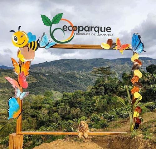 a dog sitting in front of a sign with butterflies at Ecoparque in Buesaco