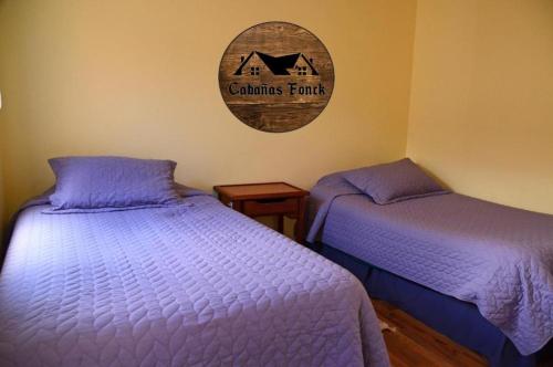 1 dormitorio con 2 camas y un cartel en la pared en Cabañas Fonck II, en Puerto Montt