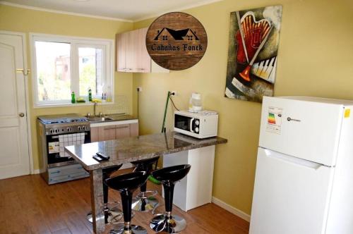 a kitchen with a white refrigerator and a counter with stools at Cabañas Fonck II in Puerto Montt