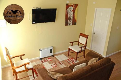 sala de estar con sofá, 2 sillas y TV en Cabañas Fonck II, en Puerto Montt