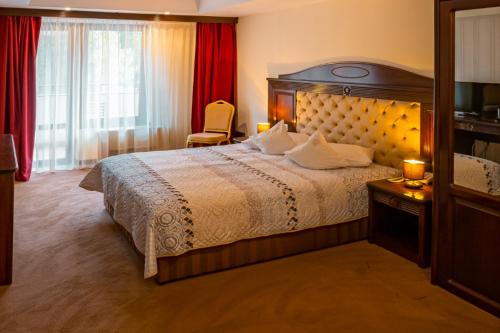 a bedroom with a large bed and a red curtain at Hotel Perla in Slănic-Moldova