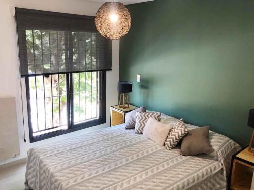 Un dormitorio con una cama grande y una pared verde en Luminoso departamento en Godoy cruz en Godoy Cruz