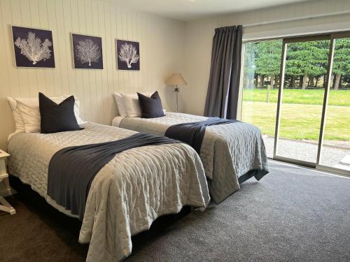a bedroom with two beds and a large window at Thistle Cottage in Ashburton