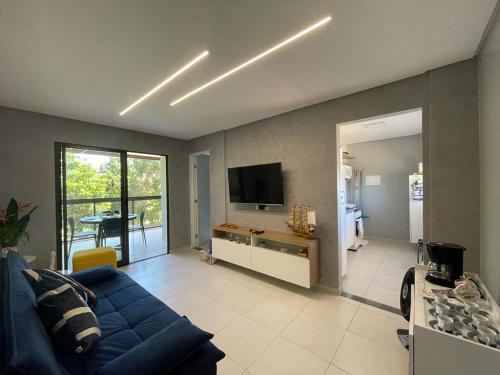 ein Wohnzimmer mit einem blauen Sofa und einem TV in der Unterkunft Apartamento na Praia do Francês in Praia do Frances