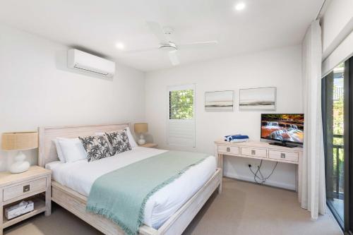 Un dormitorio con una cama y un escritorio con televisión. en Sundowner 3 - Ocean Views near Noosa Main Beach, en Noosa Heads