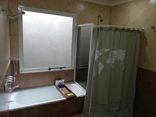 baño con cortina de ducha y ventana en La Moradita en Necochea
