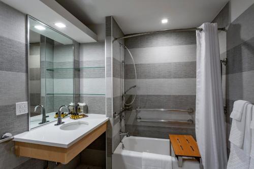 Best Western Plus Soho Hotel في نيويورك: حمام مع حوض وحوض استحمام ودش