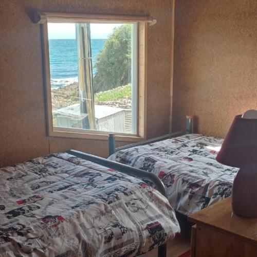 1 dormitorio con 2 camas y ventana en Refugio Hualaihue, en Hornopirén