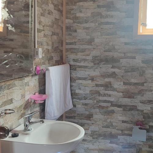 a bathroom with a white sink and a brick wall at Refugio Hualaihue in Hornopiren